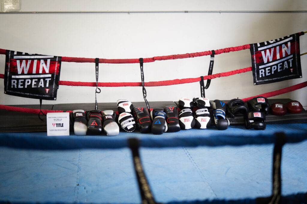 Boxing gloves laid flat on blue gym floor mats