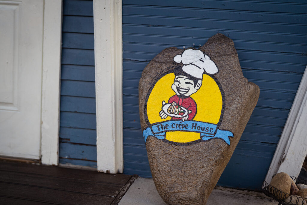 A big rock with The Crepe House logo pained onto it with vibrant colors