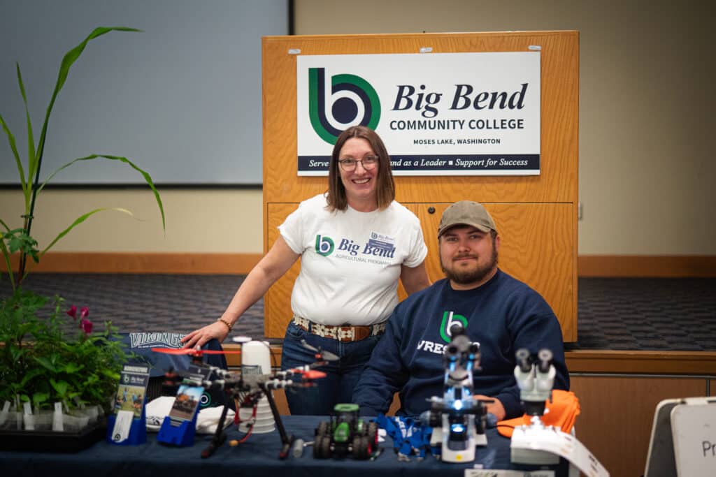 Two adults behind a table smiling at the camera at the Big Bend Community College's Job Fair