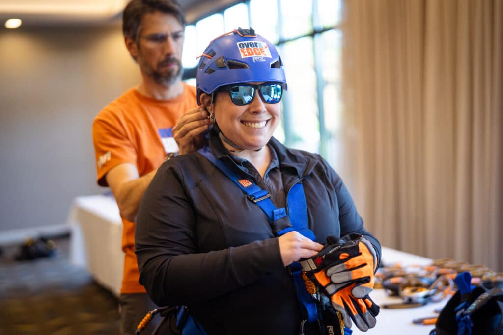 A woman smiling at the camera getting her gear ready to rappel off the Residence Inn Building