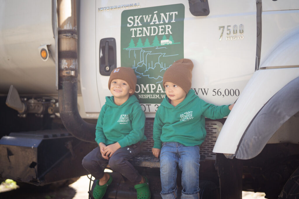 Two young boys sitting on the side of a white utility truck