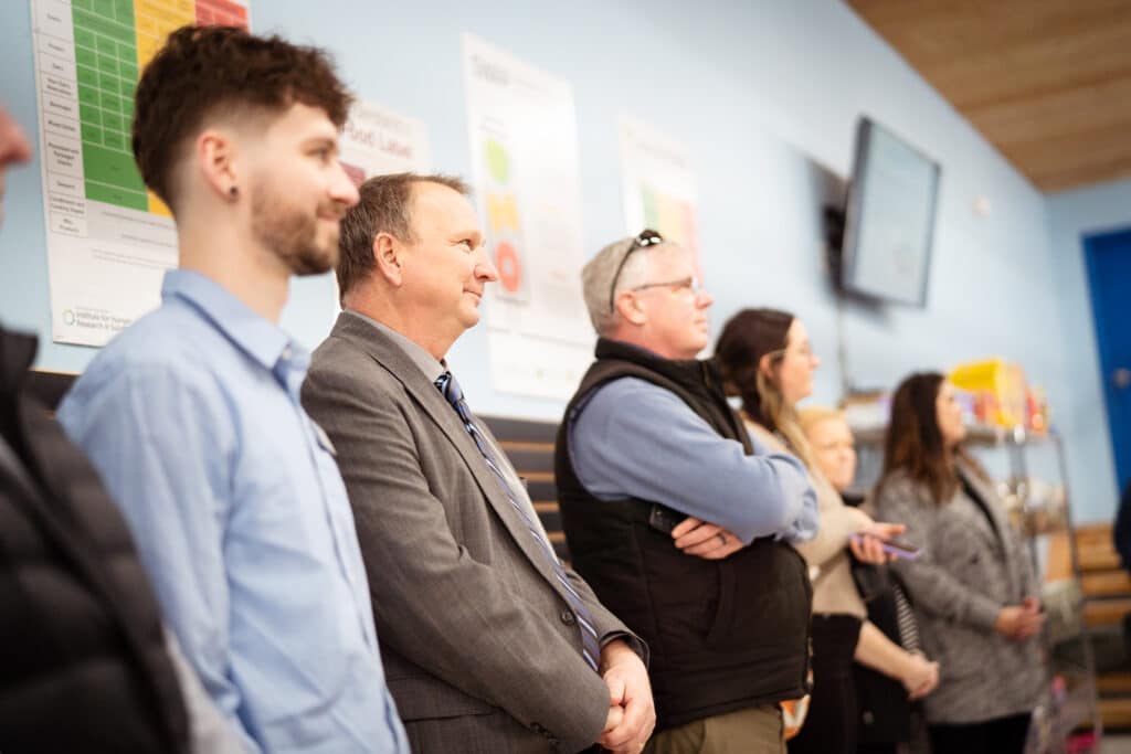 A group of adults lined up at the front of the room at CDCAC'S Food Pantry