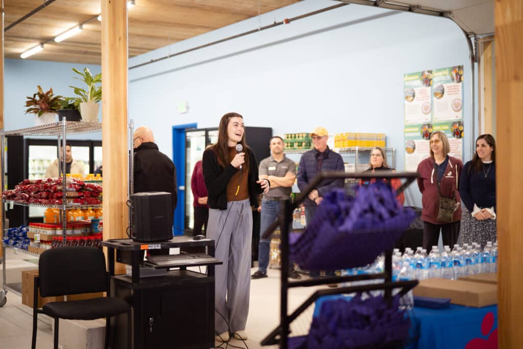 A woman talking into a mic at the CDCAC'S Food Pantry event