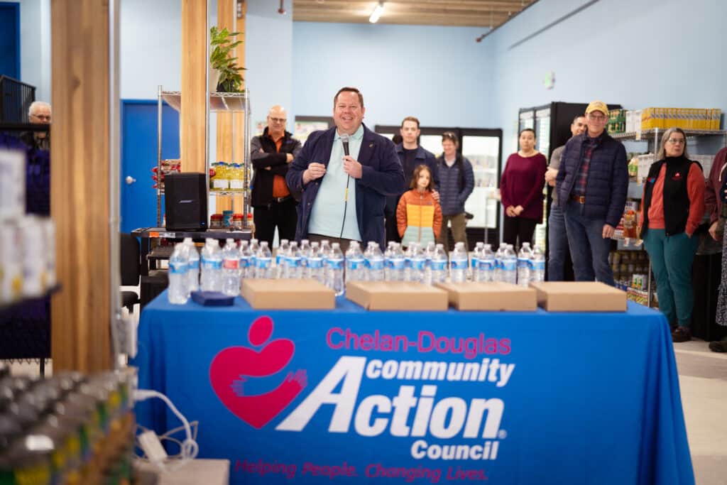 A male talking to a group of people through a mic at CDCAC's Food Pantry Event