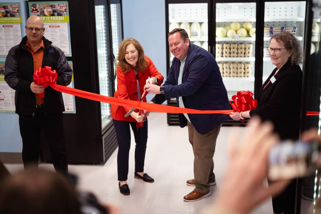 Community members and organizers cutting a ribbon at CDCAC's Food Pantry Event