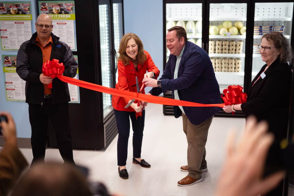 Community members and organizers cutting a ribbon at CDCAC's Food Pantry Event