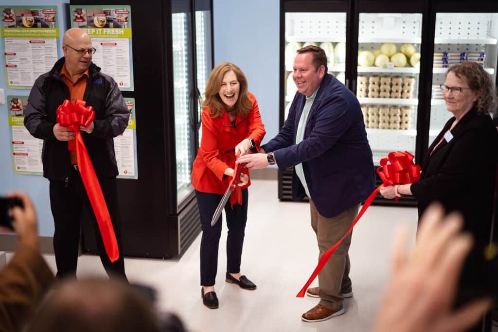 Community members and organizers cutting a ribbon at CDCAC's Food Pantry Event