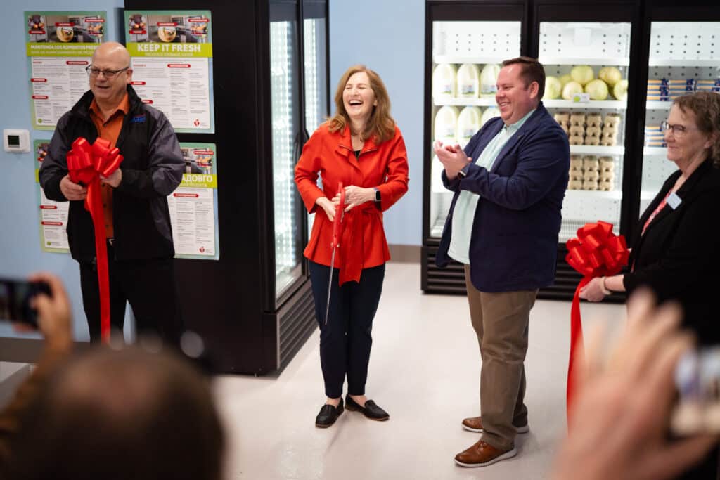 Community members and organizers cutting a ribbon at CDCAC's Food Pantry Event