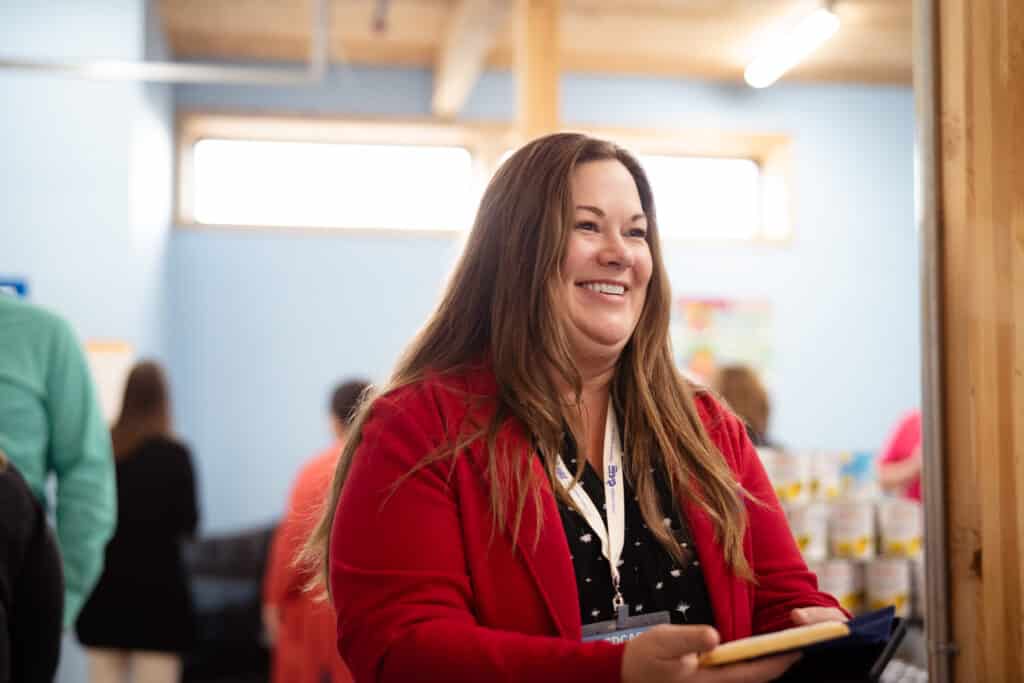 A CDCAC member. a woman with long light brown hair and a red jacket smiling