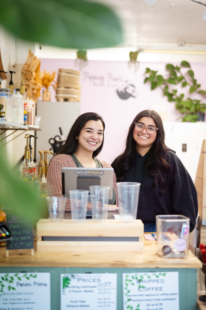 Popping Pearls Boba-9 Two women with brunette hair standing behind a desk smiling at the camera