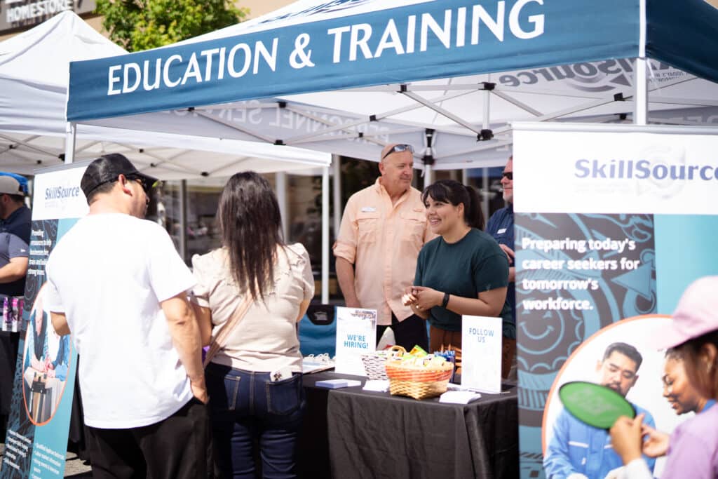 LaTerraza2024-15 Two adults talking to a woman standing behind a Education & Training booth