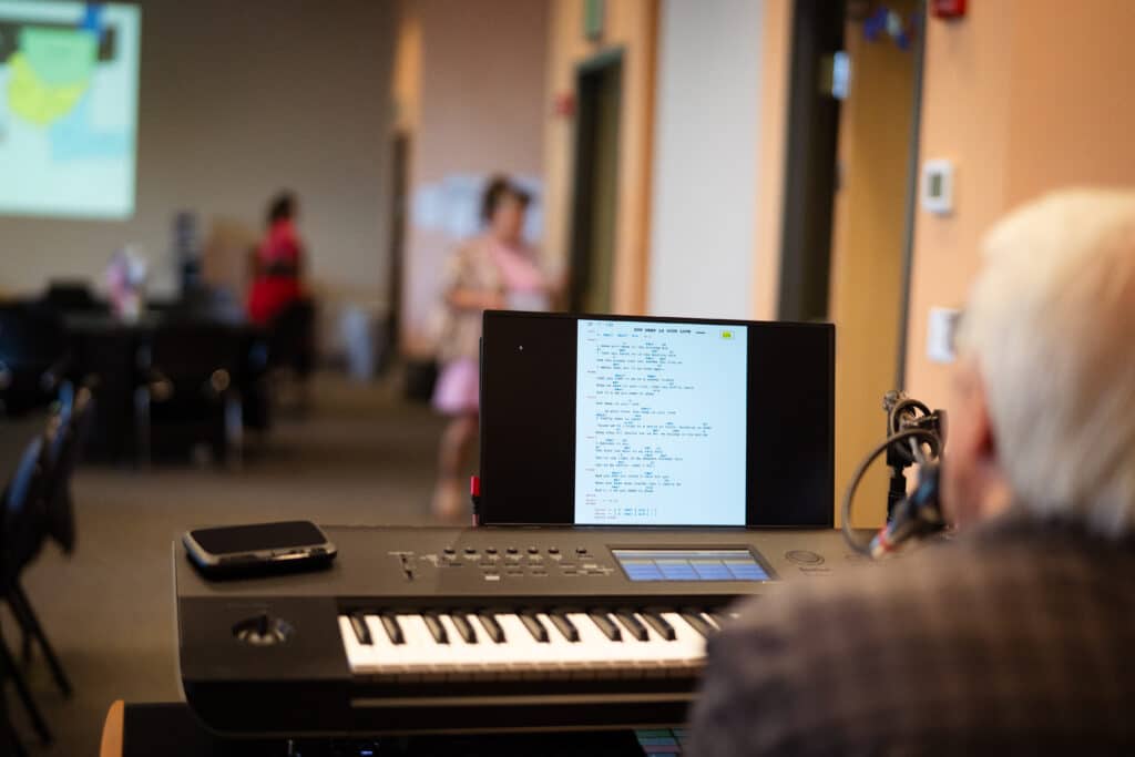 7-1-25 ML BAH-02 A man sits at an electric keyboard with a screen displaying song lyrics and chords