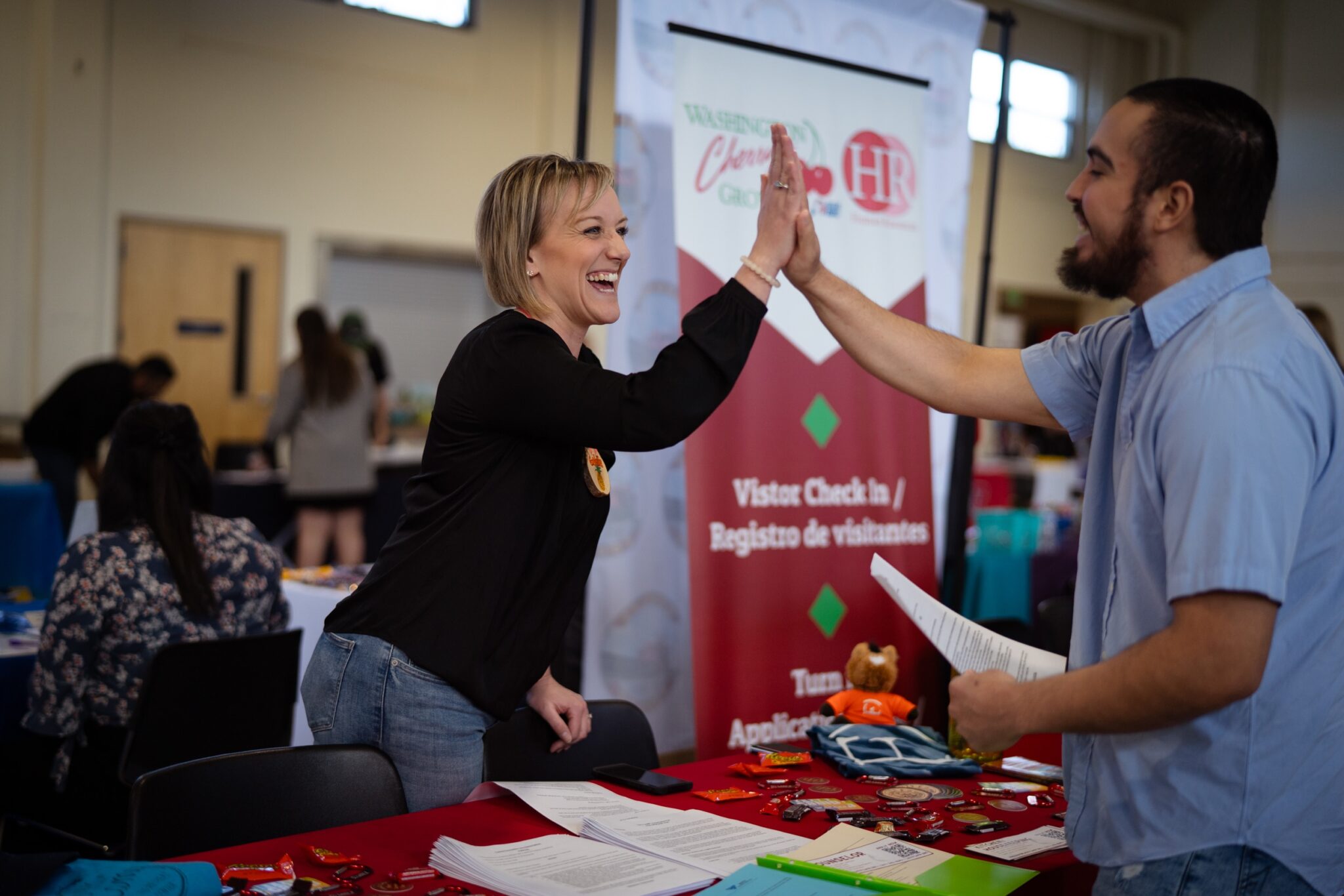 An employer at a hiring event high fives a career seeker.