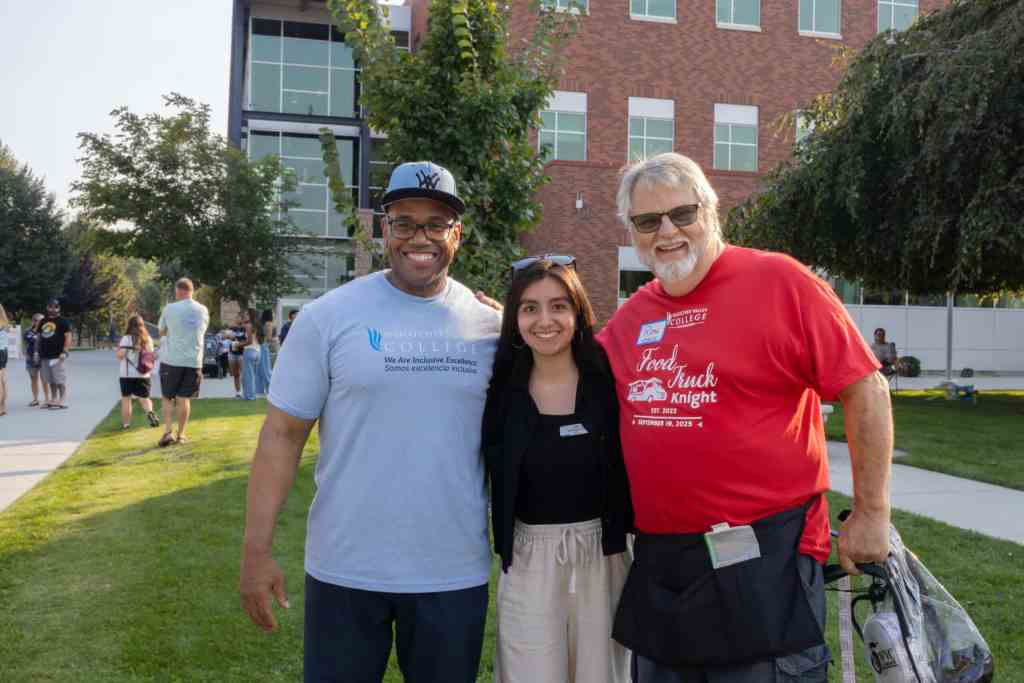 A group of 3 people, two men one woman are smiling for a photo outside of Wenatchee Valley College.