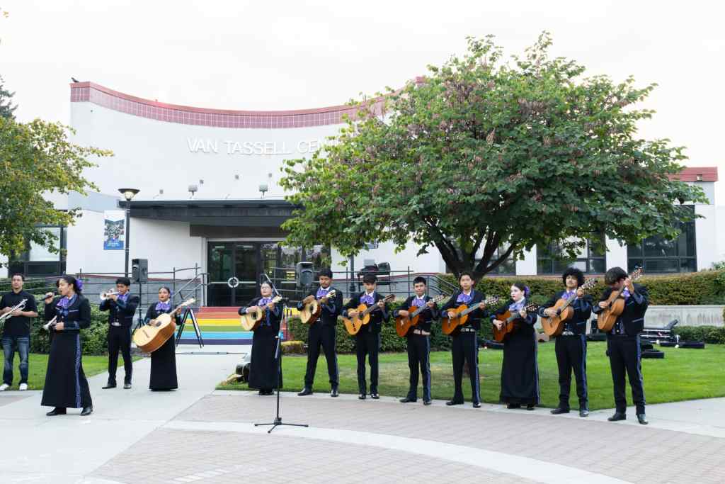 A mariachi band wearing a black outfit playing outdoors at Wenatchee Valley College.